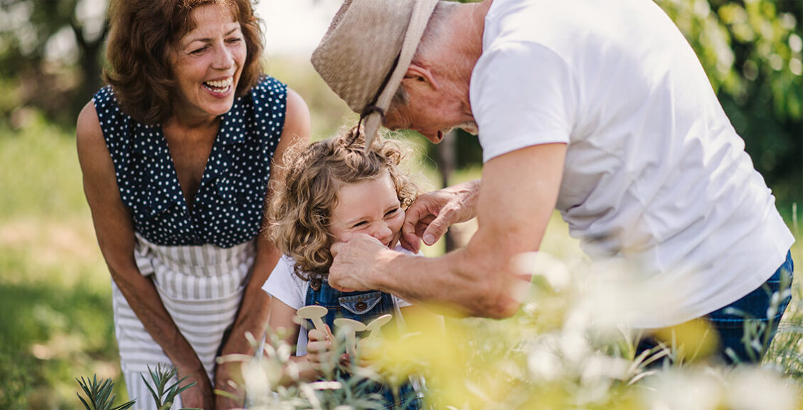 grandma and grandpa in garden with young child showing affection