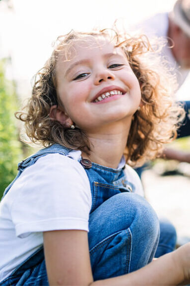 young female with curly hair smiling at camera