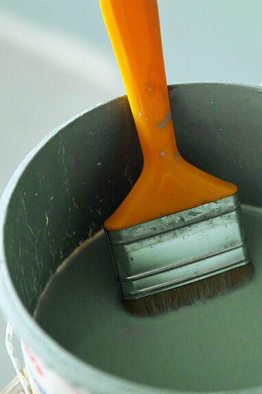 Bucket of paint with paint brush leaning on side